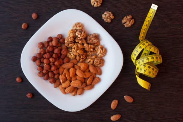 istock Various nuts with measuring tape on wooden background. 874940546