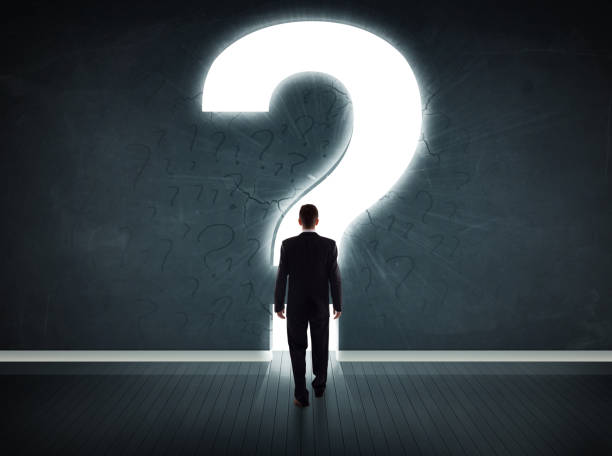 istock Business man looking at wall with a bright question mark 874951206
