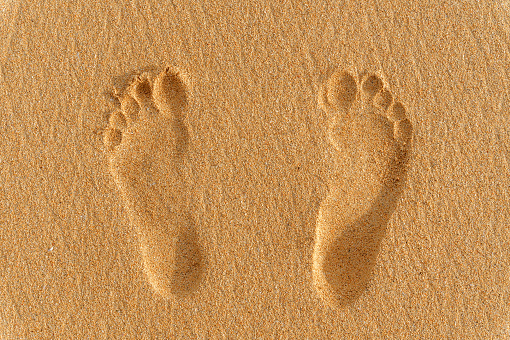foot prints or traces of two human feet on the sand. vacation concept