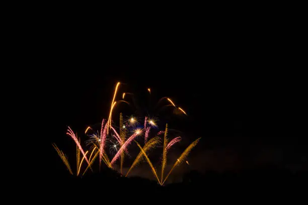 Fireworks in orange and yellow exploding in the night at fantastic party