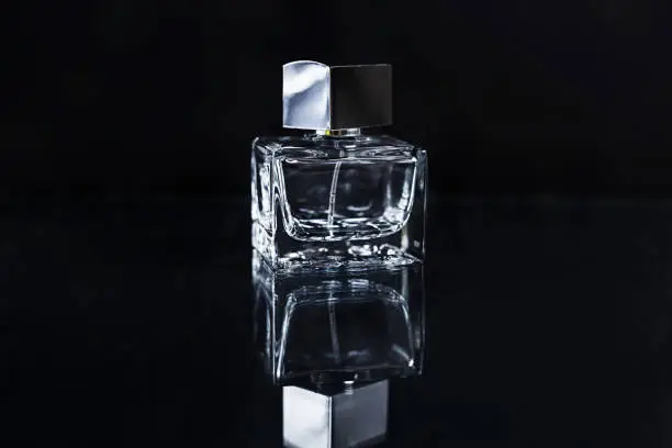 Empty bottle of perfume on a black background with reflection