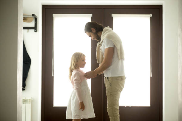 istock Caring dad dressing buttoning little daughter at home, good father 874986306