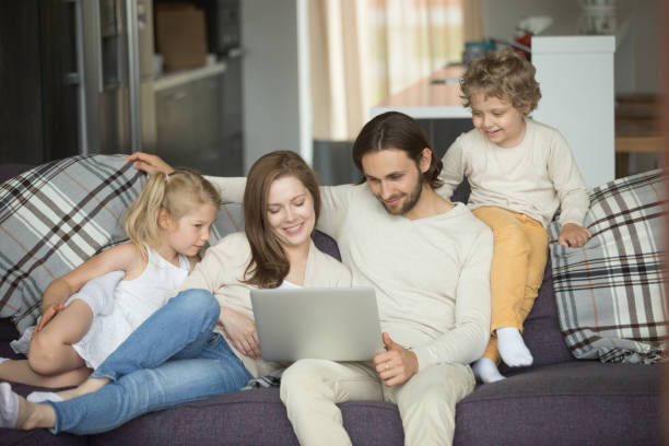 istock Happy family with kids using laptop on sofa at home 874986454