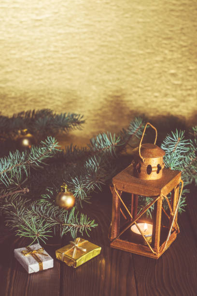 istock Lantern with a candle and Christmas tree branch on a wooden table 874987610