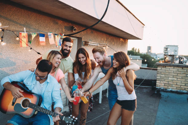 istock Group of happy friends having party on rooftop 874987688