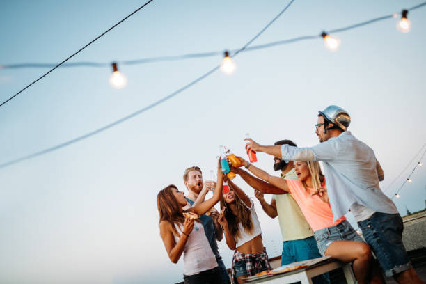 istock Group of happy friends having party on rooftop 874987982