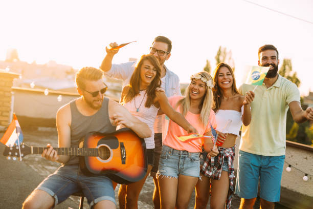 istock Group of happy friends having party on rooftop 874990846