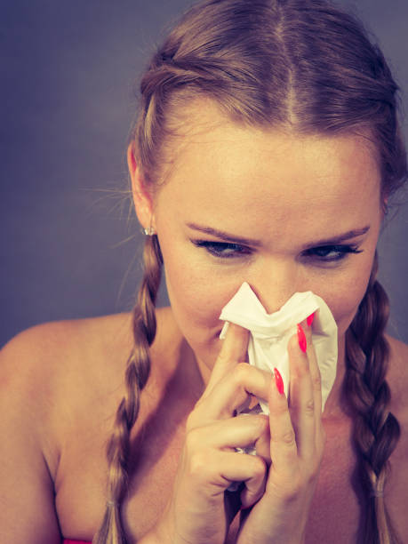 istock Woman being sick having flu sneeze into tissue 875004468