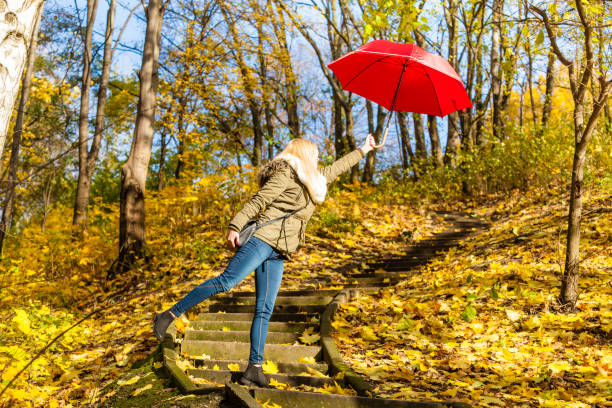 istock Woman walking in park with umbrella, strong wind 875004868