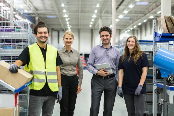 Portrait of distribution warehouse working team standing together and looking at camera