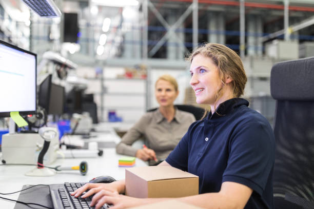 Worker preparing a package to dispatch Woman sitting at her desk with a package working on computer in warehouse. Worker preparing a package to dispatch. warehouse office stock pictures, royalty-free photos & images