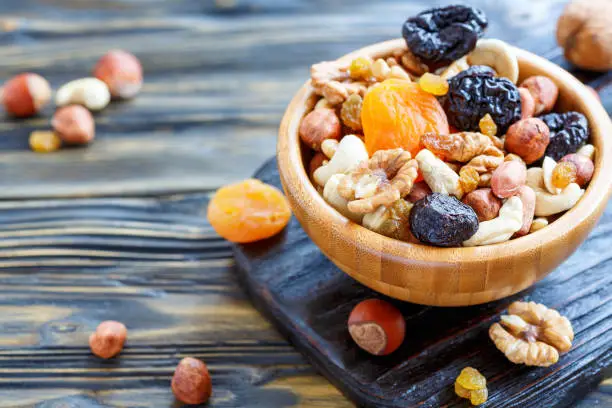 Photo of Nuts and dried fruit in a wooden bowl.