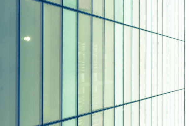 istock Light from dawn sky reflecting on the glass windows of on an office building 875021128