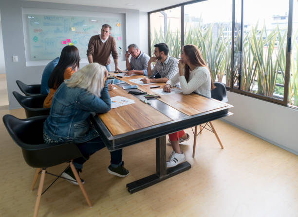 istock Man talking to a group of people in a meeting at a creative office 875023964