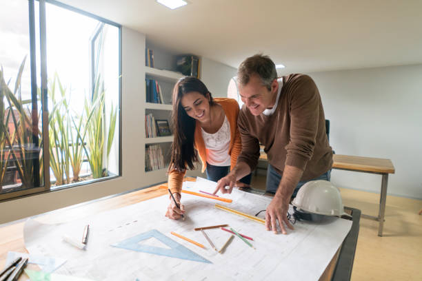 couple d’architectes travaillant au bureau de dessin d’un plan d’action - maison témoin maison photos et images de collection