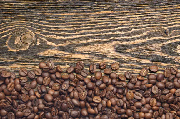 Top view of coffee beans on rustic wooden table with free space for text