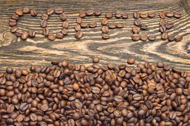 Top view of coffee beans on rustic wooden table with text coffee