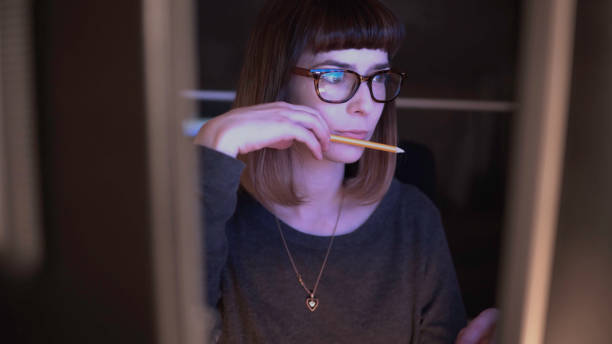 Screen choice. A pretty young woman, caught between two computer monitors is staring intently at one of them. woman examining stock pictures, royalty-free photos & images