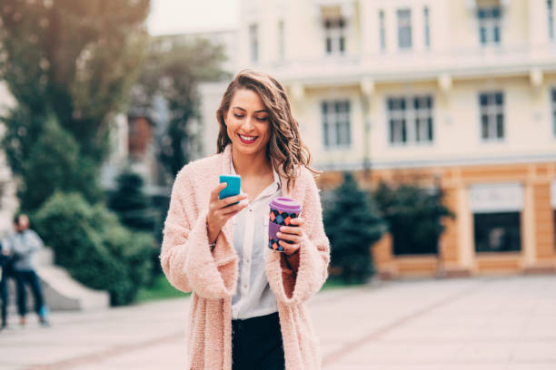 Woman texting and drinking coffee in the city