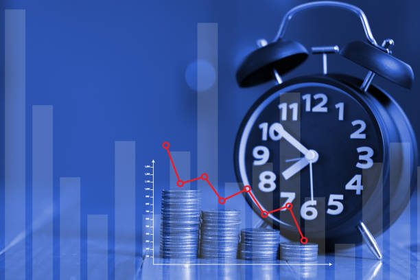 istock Alarm clock and step of coins stacks on working table with financial graph chart, time for savings money concept. 875054052