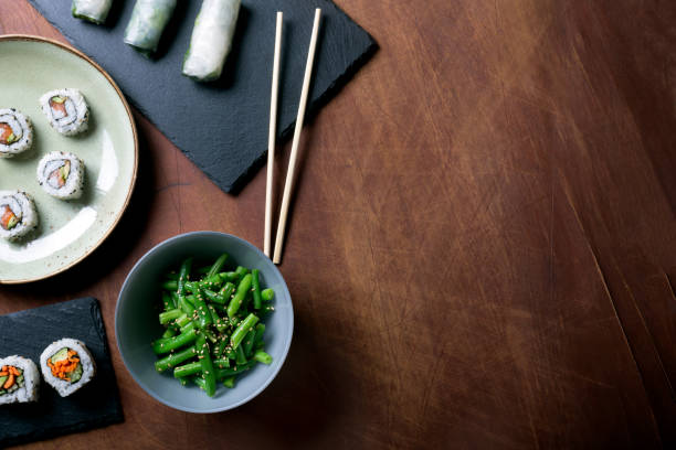 sushi giapponese e fagiolini su uno sfondo di legno scuro - japanese cuisine temaki sashimi sushi foto e immagini stock