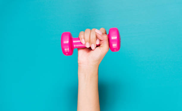 istock Closeup of hand holding pink dumbbell 875077136