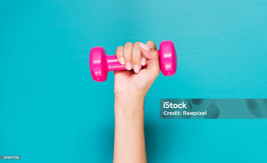 Closeup of hand holding pink dumbbell Dumbbell Stock Photo