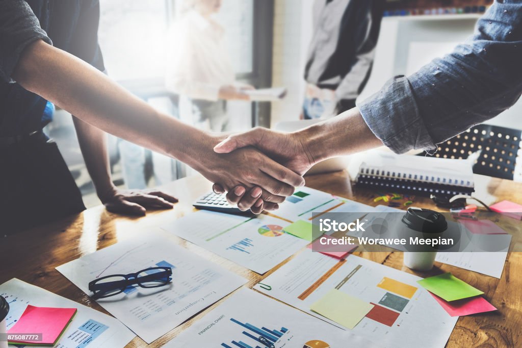 Successful businessmen partnership handshaking after acquisition and business working at background. Meeting for sign contracts and Group support concept. Coworking Stock Photo