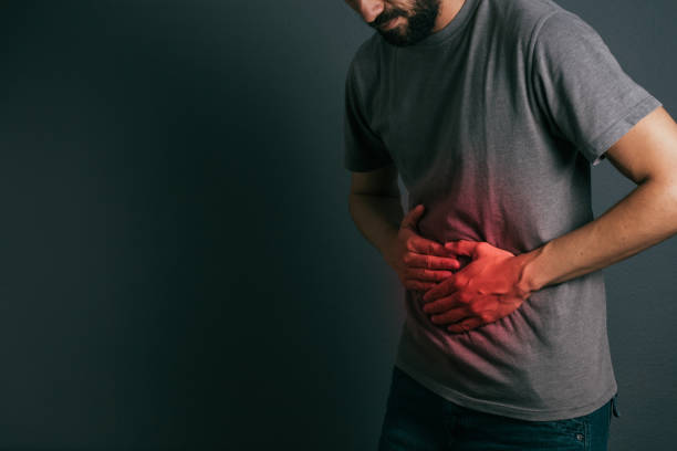 Young man suffering from stomach ache standing Young man suffering from stomach ache standing human abdomen stock pictures, royalty-free photos & images
