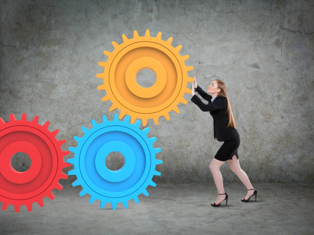 businesswoman pushing a huge gear - pushing women wall people imagens e fotografias de stock