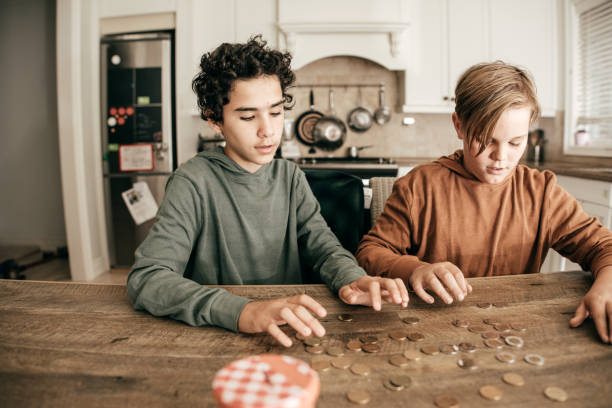 Teens counting savings Teens in domestic kitchen counting coins stock pictures, royalty-free photos & images