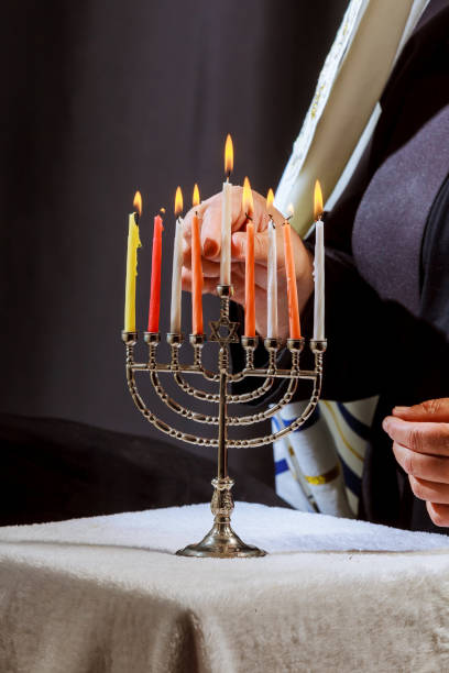 istock man hand lighting candles in menorah on table served for hanukka 875097396