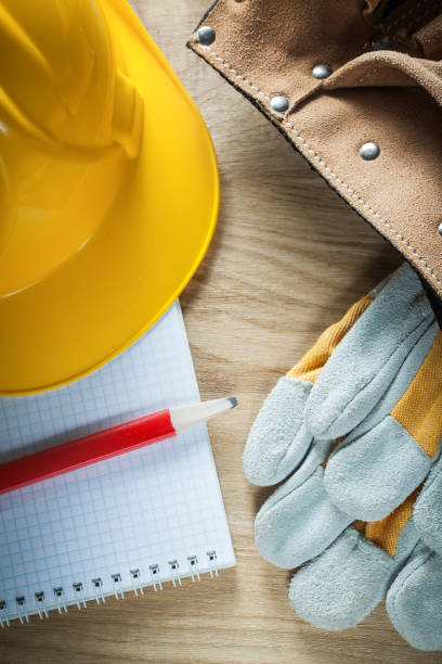 istock Leather tool belt safety gloves building helmet copybook pencil 875097848