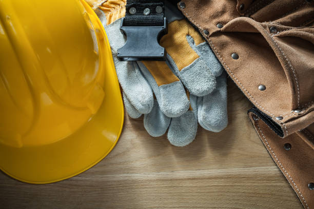 istock Leather tool belt safety gloves building helmet on wooden board 875097918
