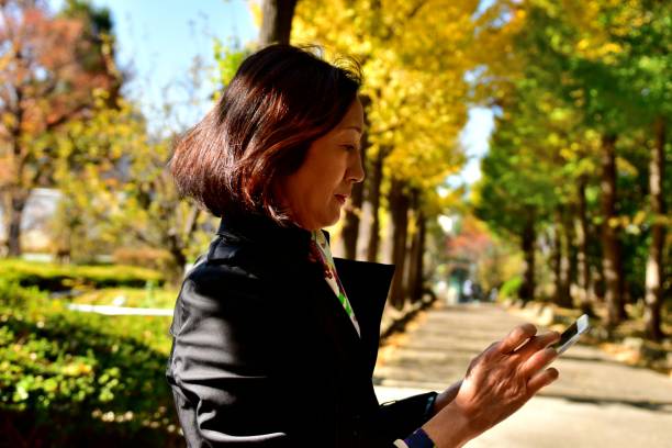 istock Japanese Woman Checking her Mobile Phone Mail in Park, Tokyo 875103606