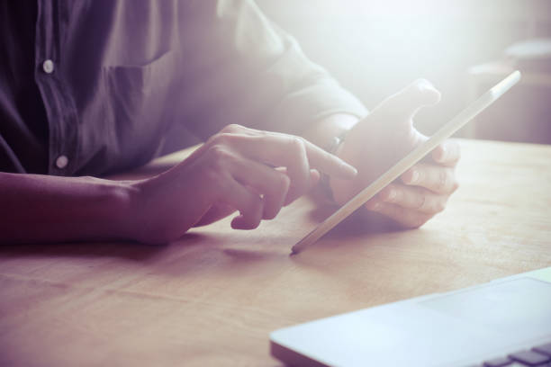 istock Close up of Male hands using tablet on the table, toned with sunlight 875103918
