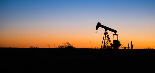 Texas Oil Pump Jack Fracking Crude Extraction Machine Sunset A device used for oil exploration in Texas oil well stock pictures, royalty-free photos & images