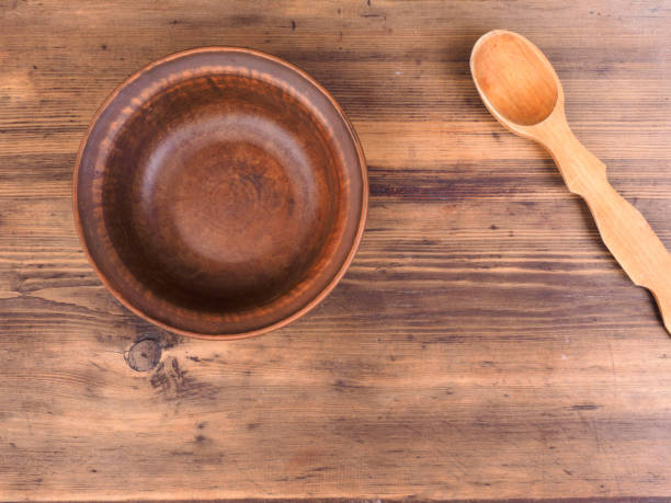 istock Empty clay bowl with wood spoon on old wooden table. Rural composition, top view. Template for menu, poster or print design 875128286