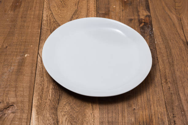 istock White Plate on brown wooden background side view 875140522