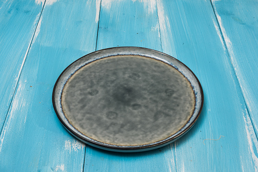 Round plate on blue wooden table with perspective side view