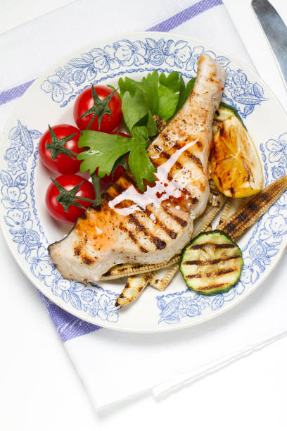 istock Grilled swordfish steak, young corn, zucchini, lemon, cherry tomatoes, chili sauce and celery leaf 875147662