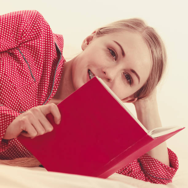 istock Woman relaxing in bed reading book 875147710