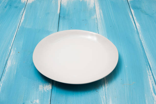 White Round plate on blue wooden table with perspective side view