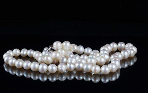 istock Beads of pearls on a black background. 875159684