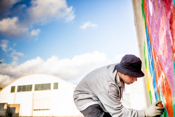 istock Late Teen Graffiti Artist Drawing Graffiti on Wall 875160980