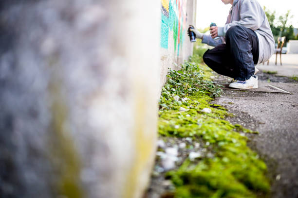 Late Teen Graffiti Artist Drawing Graffiti on Wall.