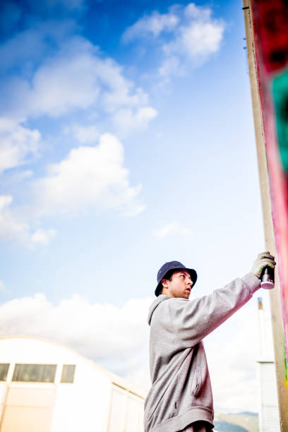 Young woman creating mural on facade of the city building. Dressed in work clothes. Exterior of busy downtown street in Toronto, Canada.