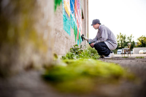 istock Late Teen Graffiti Artist Drawing Graffiti on Wall 875161032