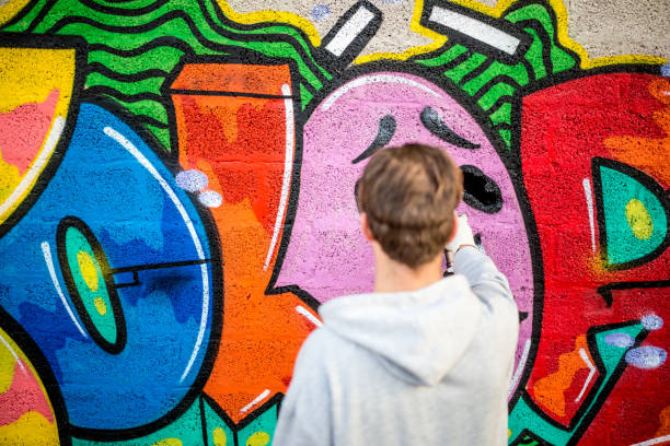 istock Late Teen Graffiti Artist Drawing Graffiti on Wall 875161120