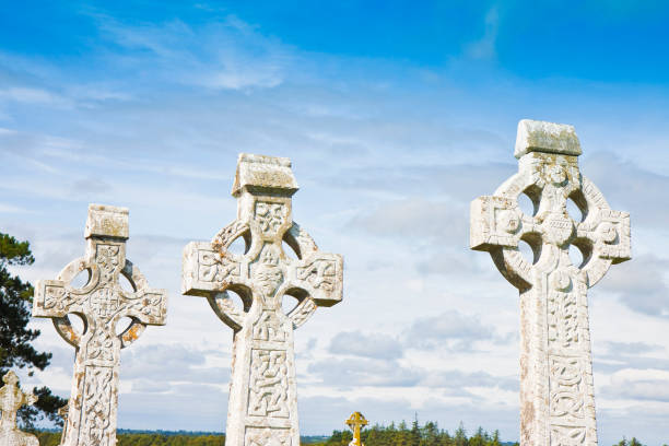 istock Celtic carved stone cross against a sky background - image with copy space 875161384